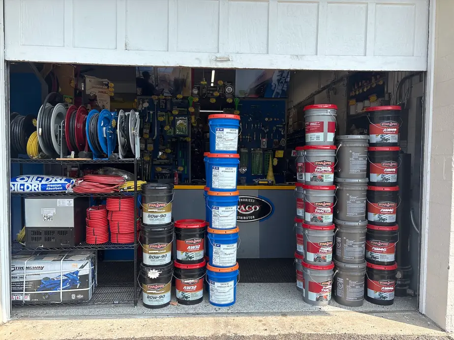 The open bay door at C & C Hydraulics: Graco hose reels, red air hose and stacked five-gallon lubricant pails in front of the authorized GRACO distributor sign